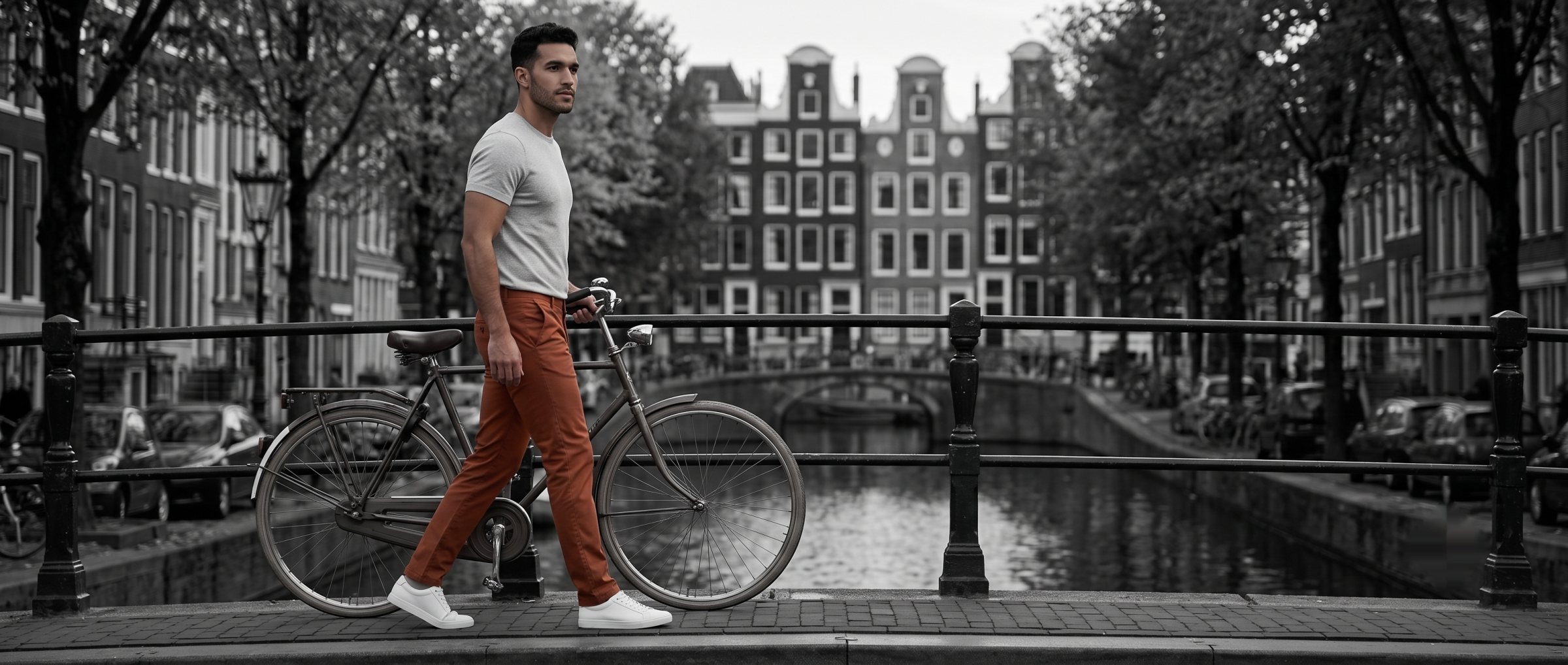 A man walking his bicycle over a canal bridge in clay Landivar chinos